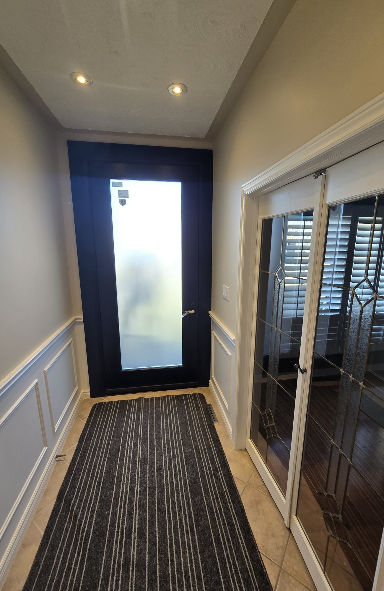 Interior view of a dark entrance door with a full-height privacy-glass panel