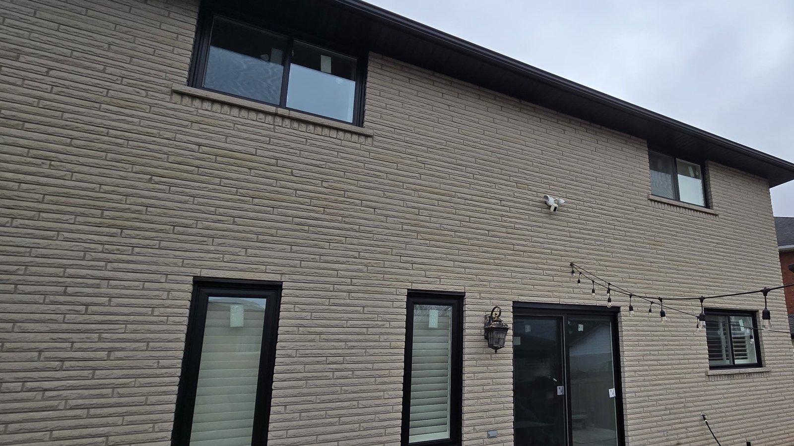 Completed Hamilton-area home with dark-framed windows and a patio door