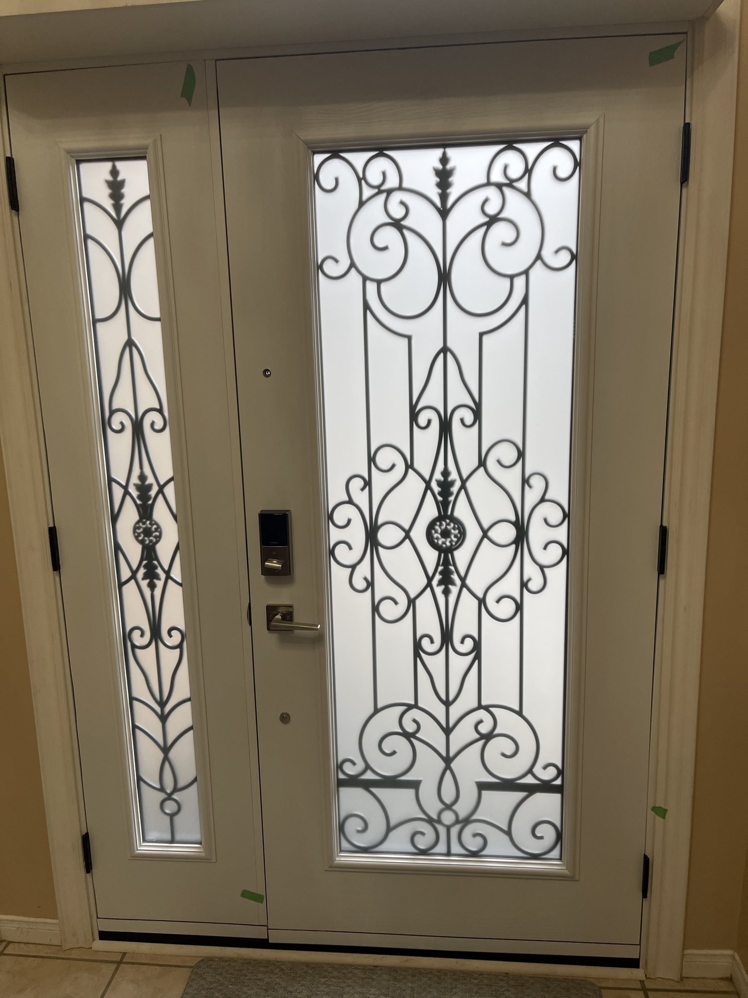 Interior view of decorative wrought-scroll glass in a front door and sidelight