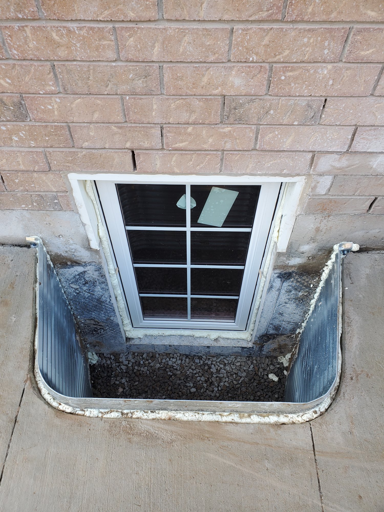 White casement egress window with colonial grilles in a rebuilt basement window well